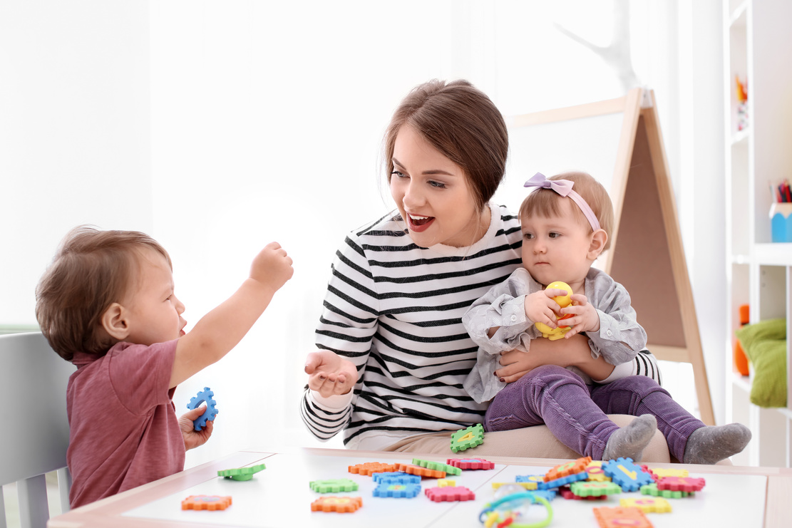 Young Woman Playing with Cute Little Children 